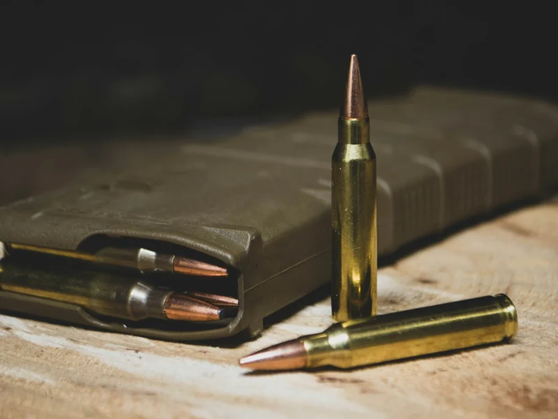 Brass rifle cartridges beside a loaded magazine